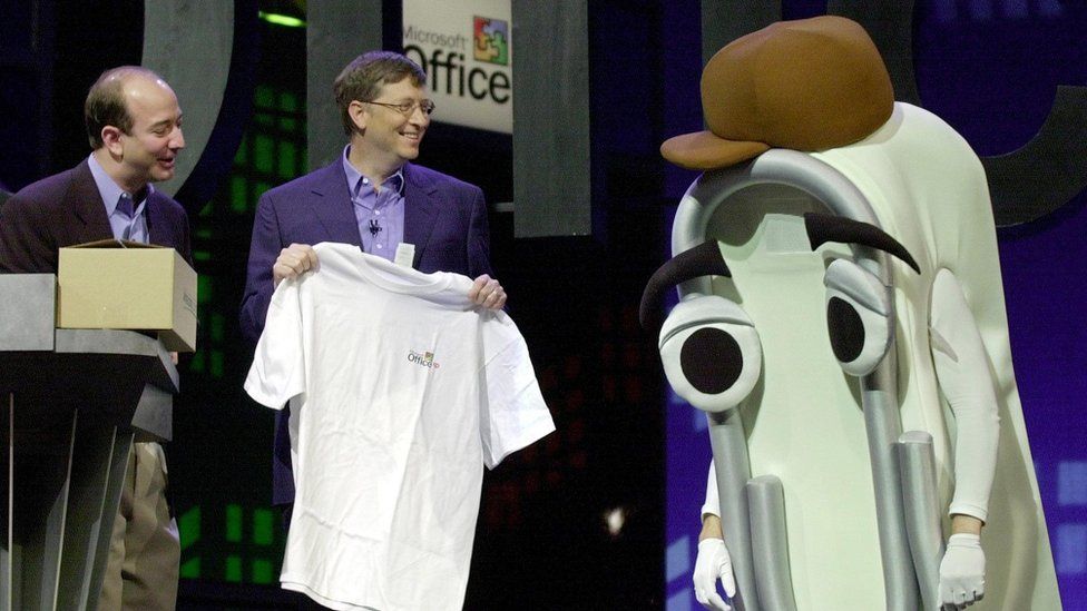 Microsoft co-founder Bill Gates presents Clippy with a retirement gift, a human-sized Office XP T-shirt, in 2001, as Amazon head Jeff Bezos watches