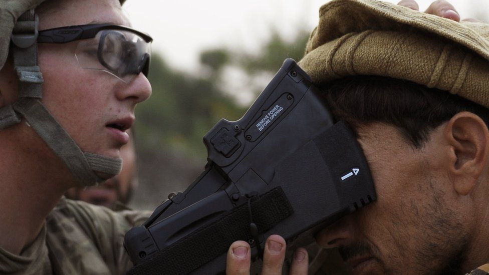 A US solider collects biometric information from a villager in 2012