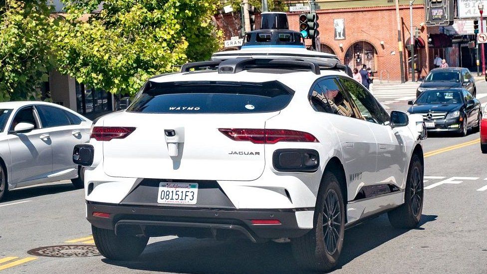 Беспилотные автомобили Waymo забили тупик на улице Сан-Франциско 1 Image caption, Waymo is trying out self-driving cars with a human "safety driver" on board