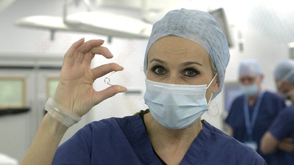 Ведущая BBC Click Лара Левингтон держит в руках образец пружины, которая вставляется в череп Арчи