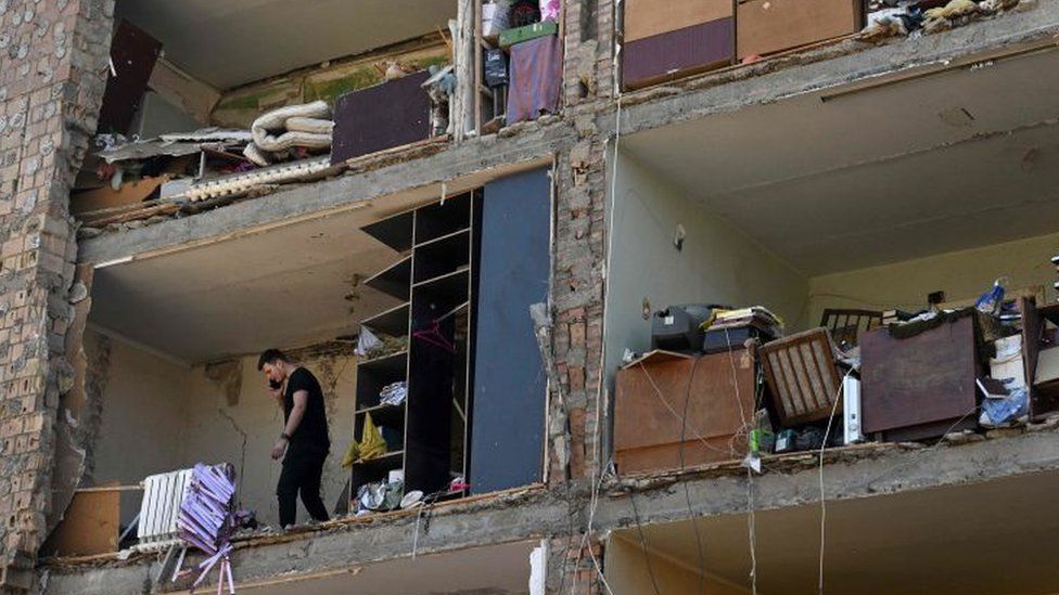 Мужчина разговаривает по мобильному телефону в квартире с отсутствующей наружной стеной из-за российского обстрела