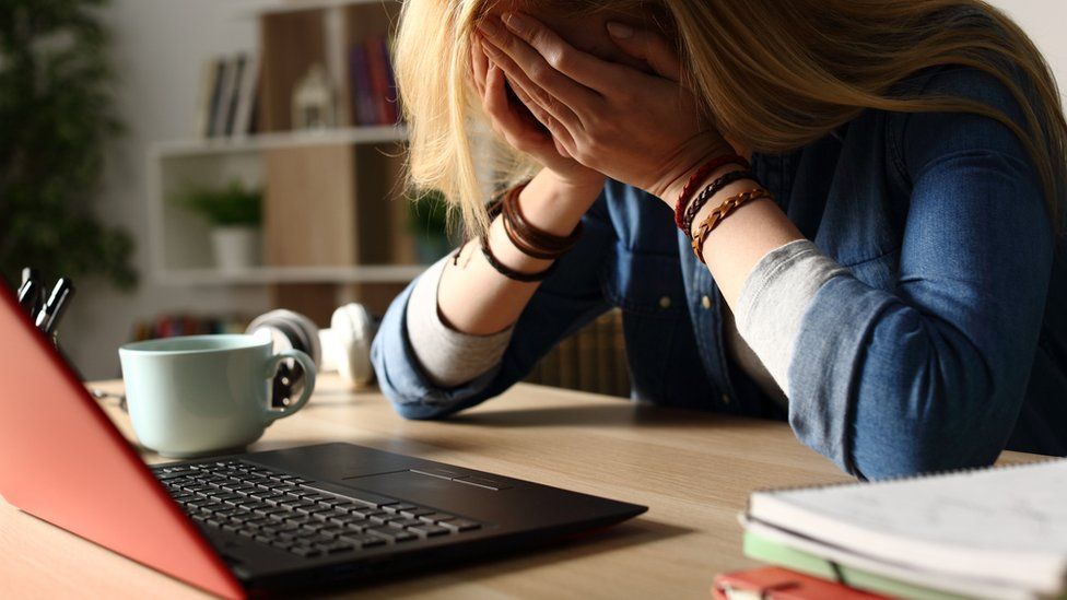 Компании широкополосного доступа. Stock image of a sad woman head in hands in front of a laptop