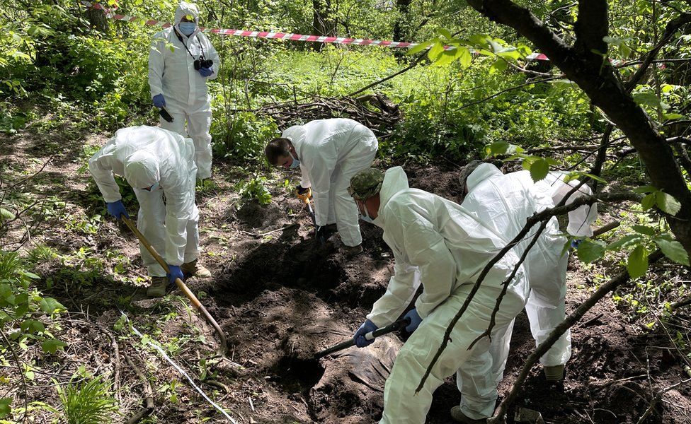 Украинская команда судмедэкспертов извлекает тело молодого российского солдата из неглубокой могилы на окраине Киева