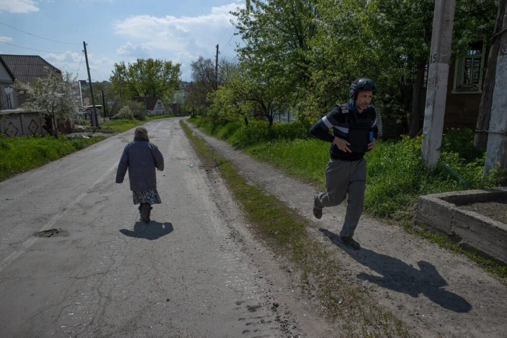 Олег, справа, строительный рабочий, ставший волонтером церкви в Харькове, бежит предупредить жителей Руска Лозова об эвакуации.