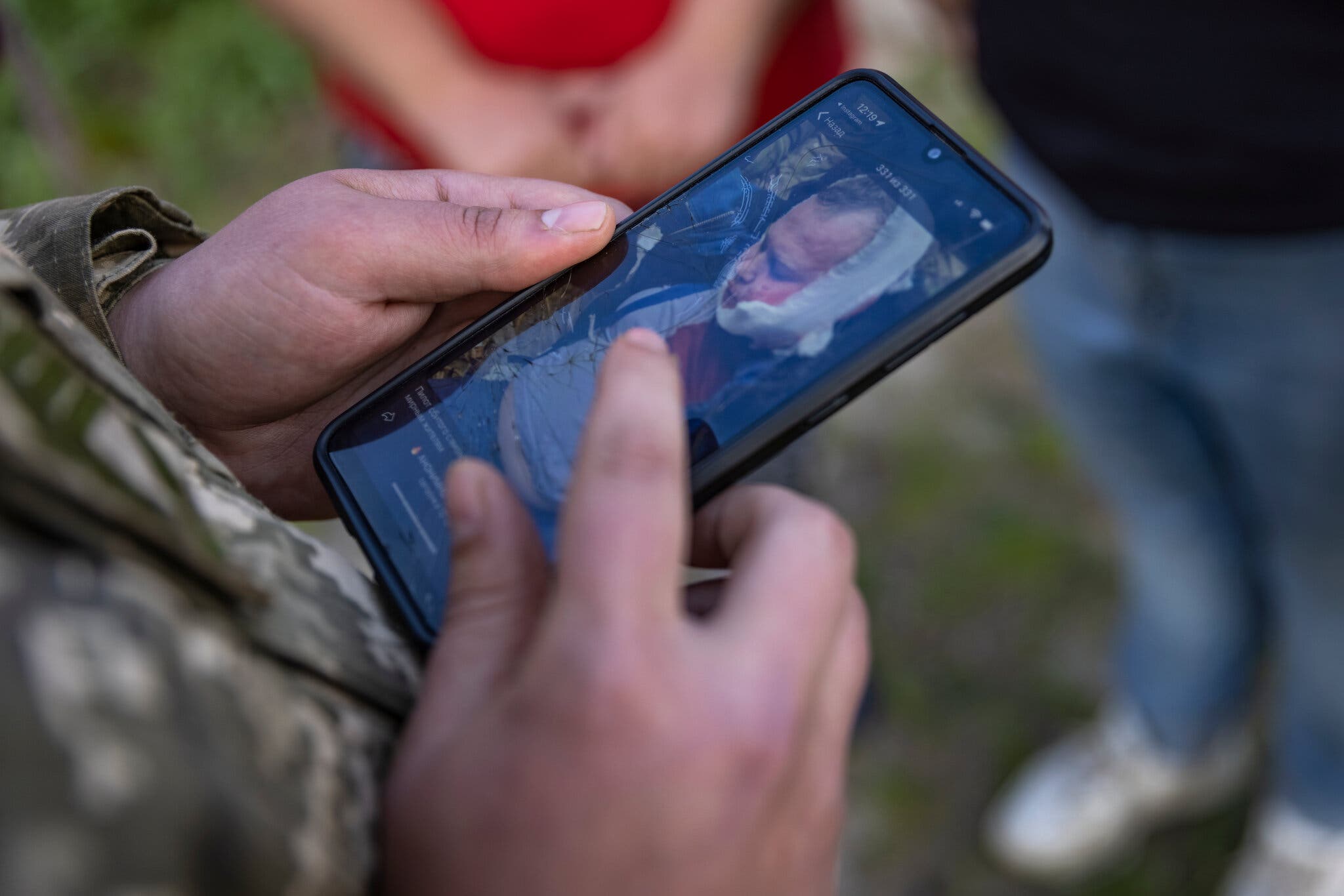Украинский солдат с мобильным телефоном показывает фотографию российского пилота, захваченного в плен в Чернигове