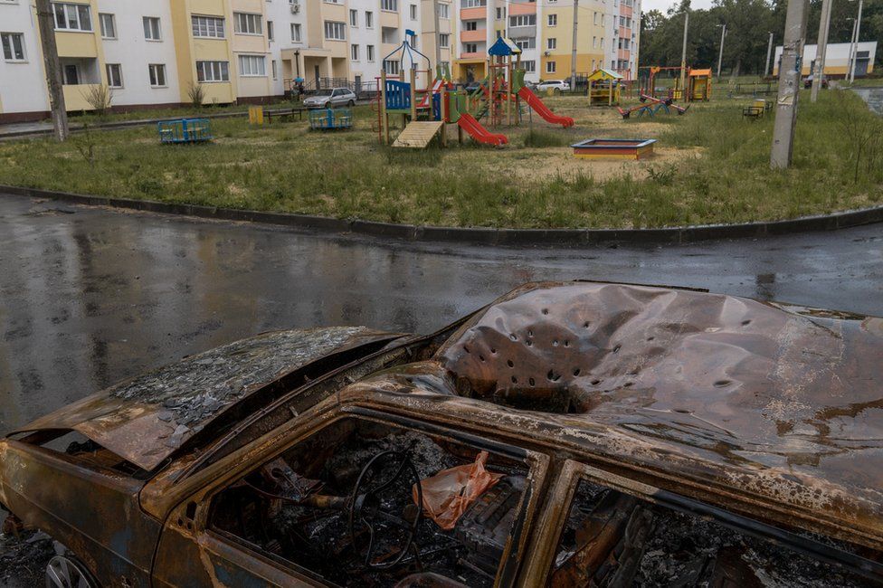 , Distinctive marks from a cluster munition in the roof of a car next to a playground in Kharkiv (Joel Gunter/BBC)