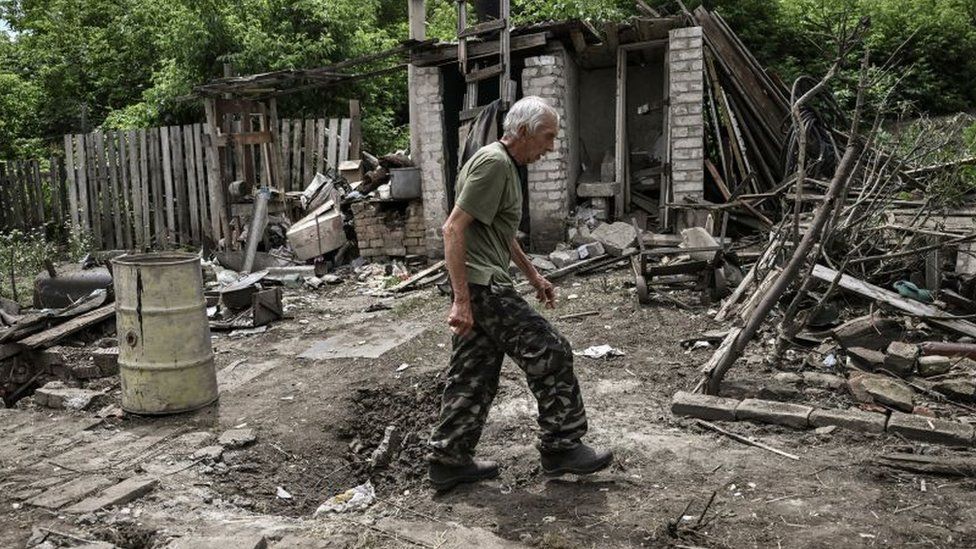 город, A man walks through the yard of a damaged house after shelling in which two people were killed in Lysychansk