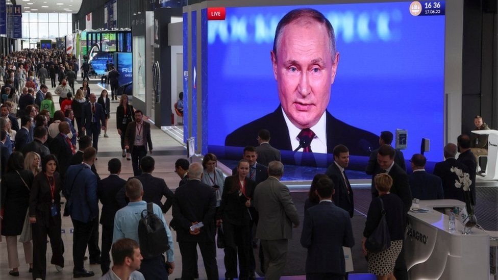 Participants gather near a screen showing Russian President Vladimir Putin, who delivers a speech at the St. Petersburg International Economic Forum (SPIEF) in Saint Petersburg, Russia June 17, 2022.