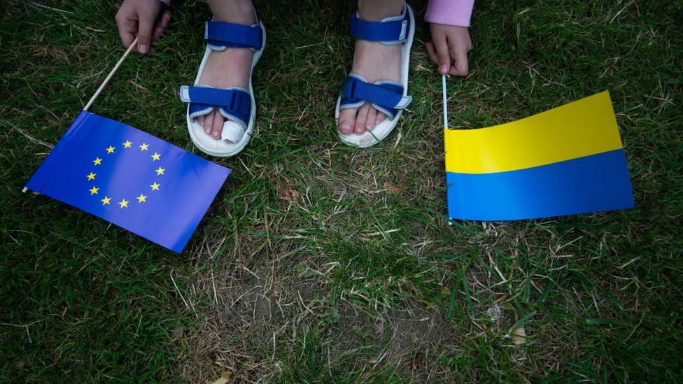 Украинская девочка держит флаг ЕС и украинский флаг во время митинга в Германии