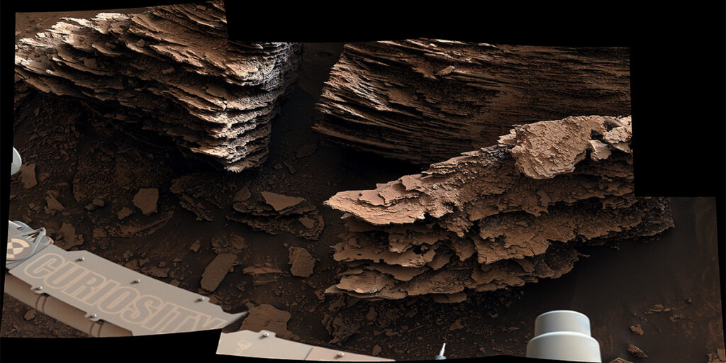 Мачтовая камера Кьюриосити видит чешуйчатые русловые камни: Марсоход НАСА Кьюриосити запечатлел этот вид слоистых, чешуйчатых камней, которые, предположительно, образовались в древнем русле ручья или небольшого пруда. Шесть изображений, составляющих эту мозаику, были сделаны с помощью мачтовой камеры Кьюриосити, или Mastcam, 2 июня 2022 года, на 3492-й марсианский день, или сол, миссии.