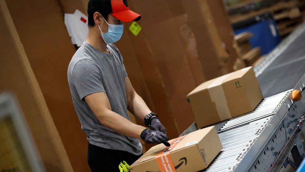 Рабочий перемещает коробки с товарами для сканирования и отправки на грузовики во время работы в центре выполнения заказов Amazon в Роббинсвилле, штат Нью-Джерси, США, 29 ноября 2021 года.