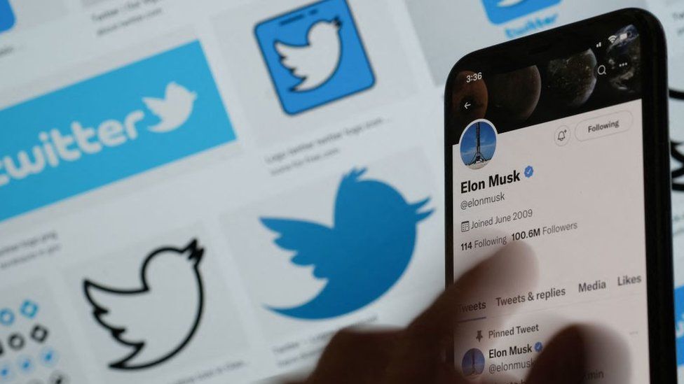 Illustration photo of Elon Musk's twitter account on a mobile phone in front of Twitter logos