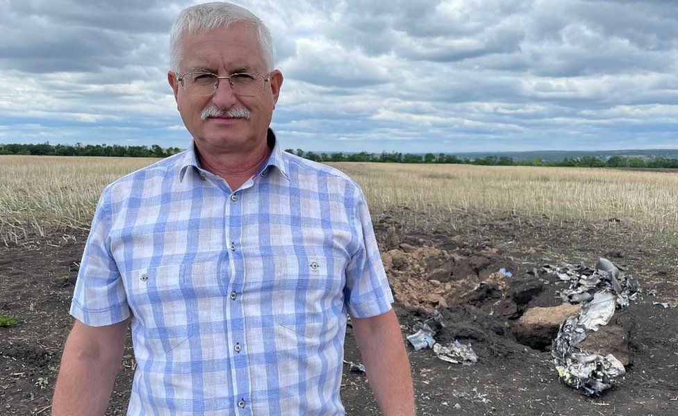 Sergei Kurinniy next to rocket debris on his farm