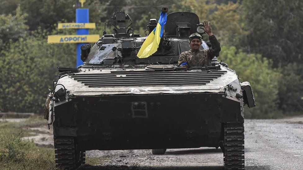 A soldier waves from a Ukrainian vehicle as it travels towards to the frontline near Kharkiv