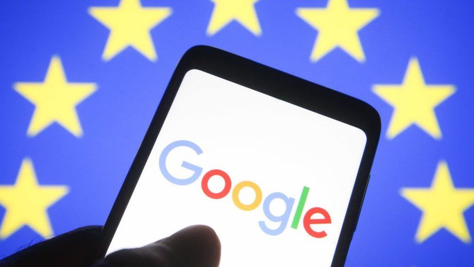 Smartphone screen displays Google logo against backdrop of EU flag