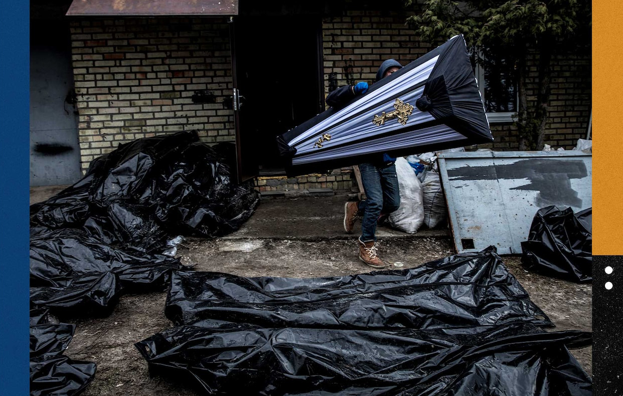 Мужчина несет гроб мимо мешков с телами, когда полиция расследует сотни убийств в Буче.