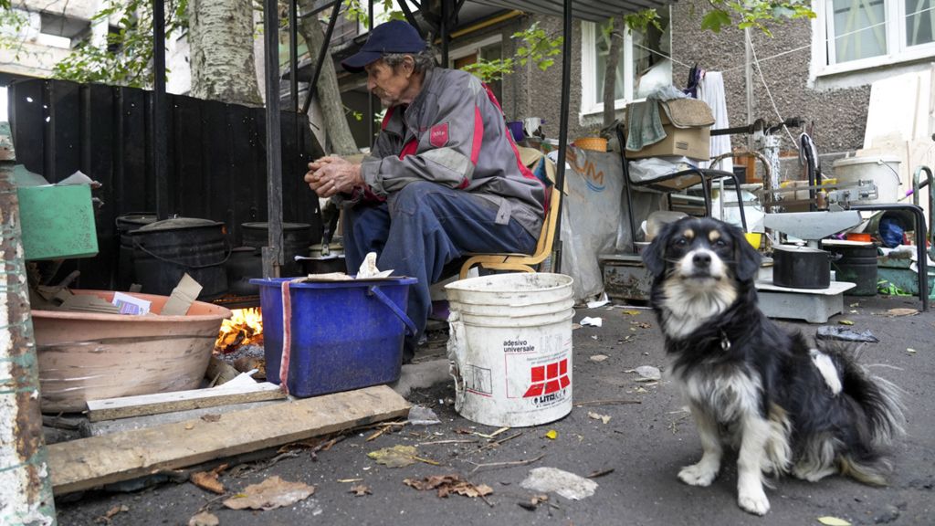 A man sits by a makeshift stove to keep warm - Mariupol, 29 September 2022