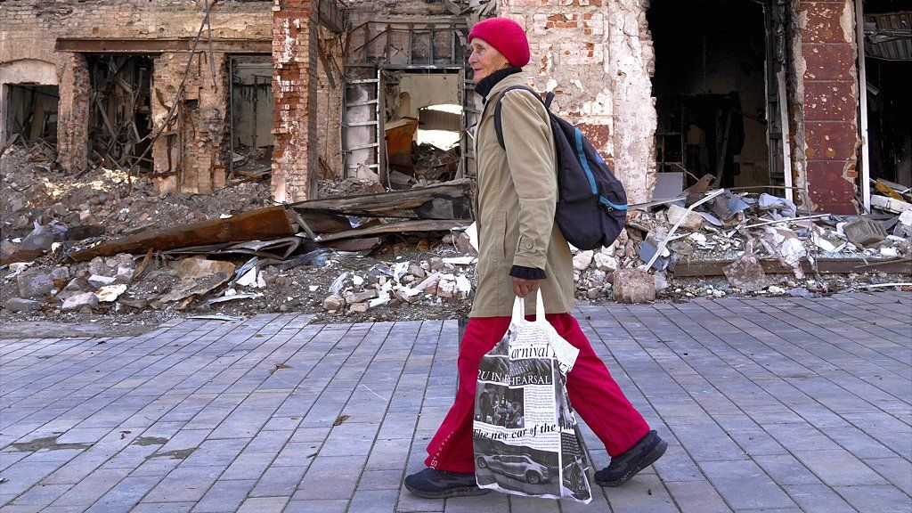 A woman walks past destroyed buildings in Mariupol - 29 September 2022