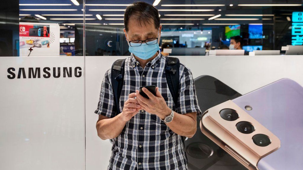A man stands in front of a store selling Samsung phones in Hong Kong.