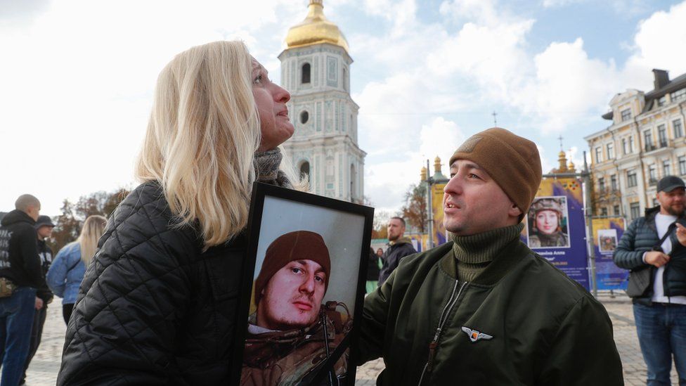 Natalia reacts as she holds a portrait of her lost son at a military commemoration in Kyiv on Friday