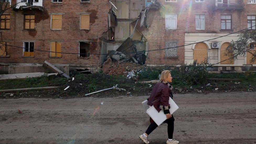 A woman walks past a building damaged by missile strikes in the eastern Donbas region of Bakhmut, Ukraine