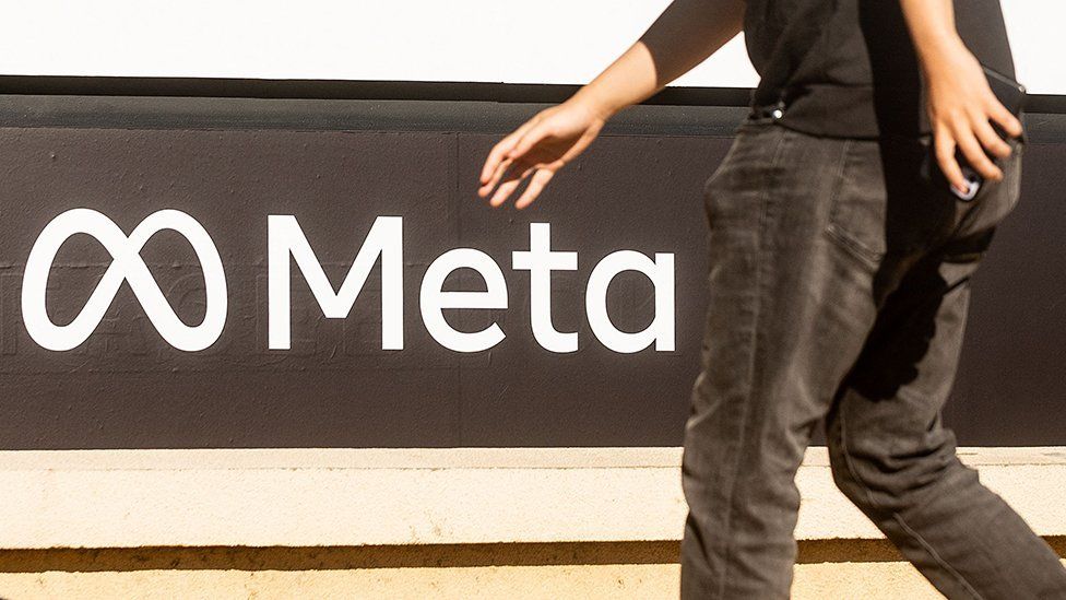 A person walks past the Meta logo