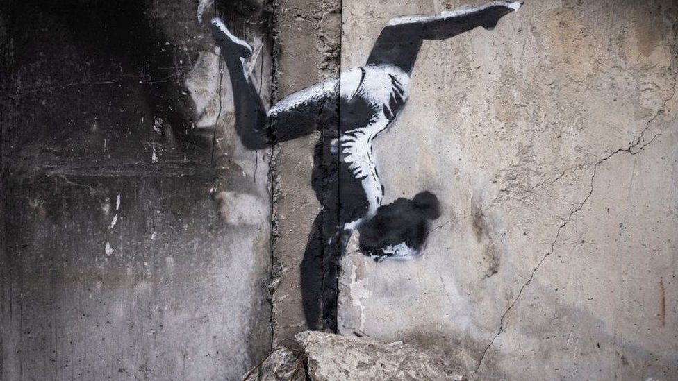 Граффити Бэнкси с изображением гимнастки, выполняющей стойку на руках, нарисованное на разрушенном здании в Бородянке