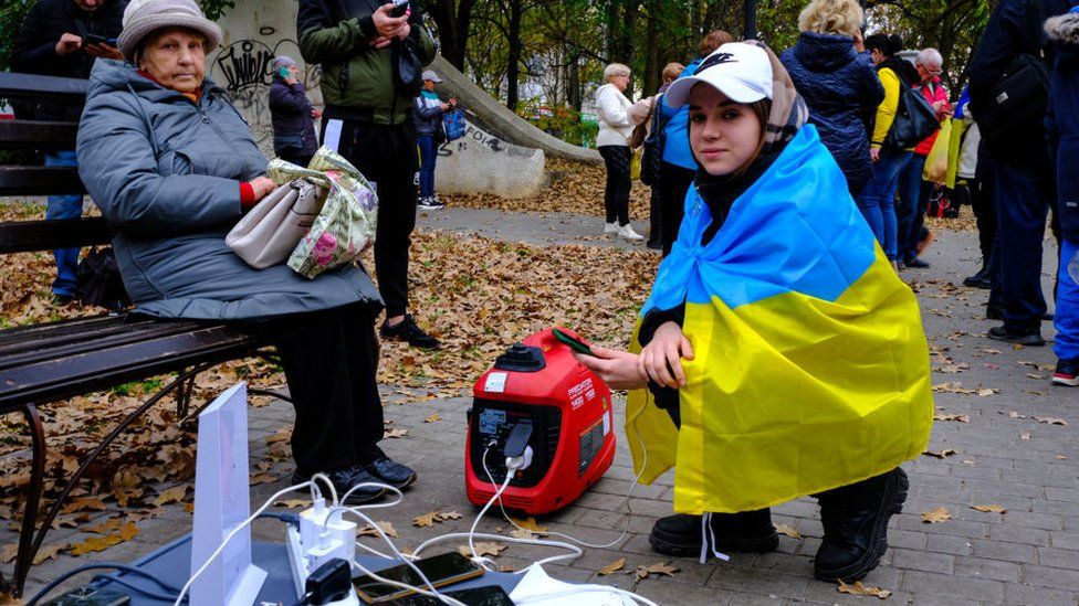 People in Ukraine use generators to charge their phones during blackouts