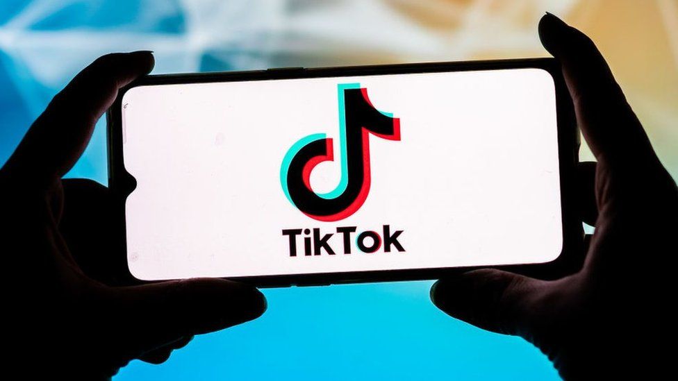 The TikTok logo is displayed on a smartphone.