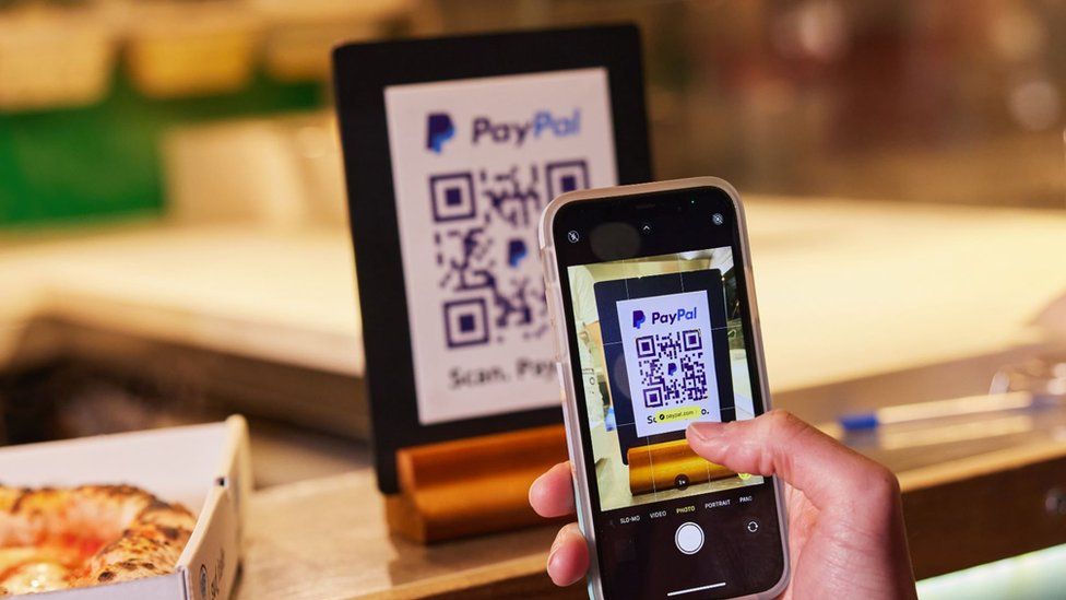 Person scans QR code with PayPal app.