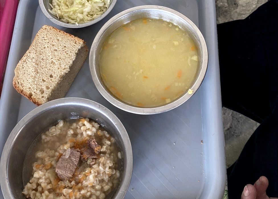 The prisoners eat a lunch of bread, corn soup, and a bowl of barley and meat