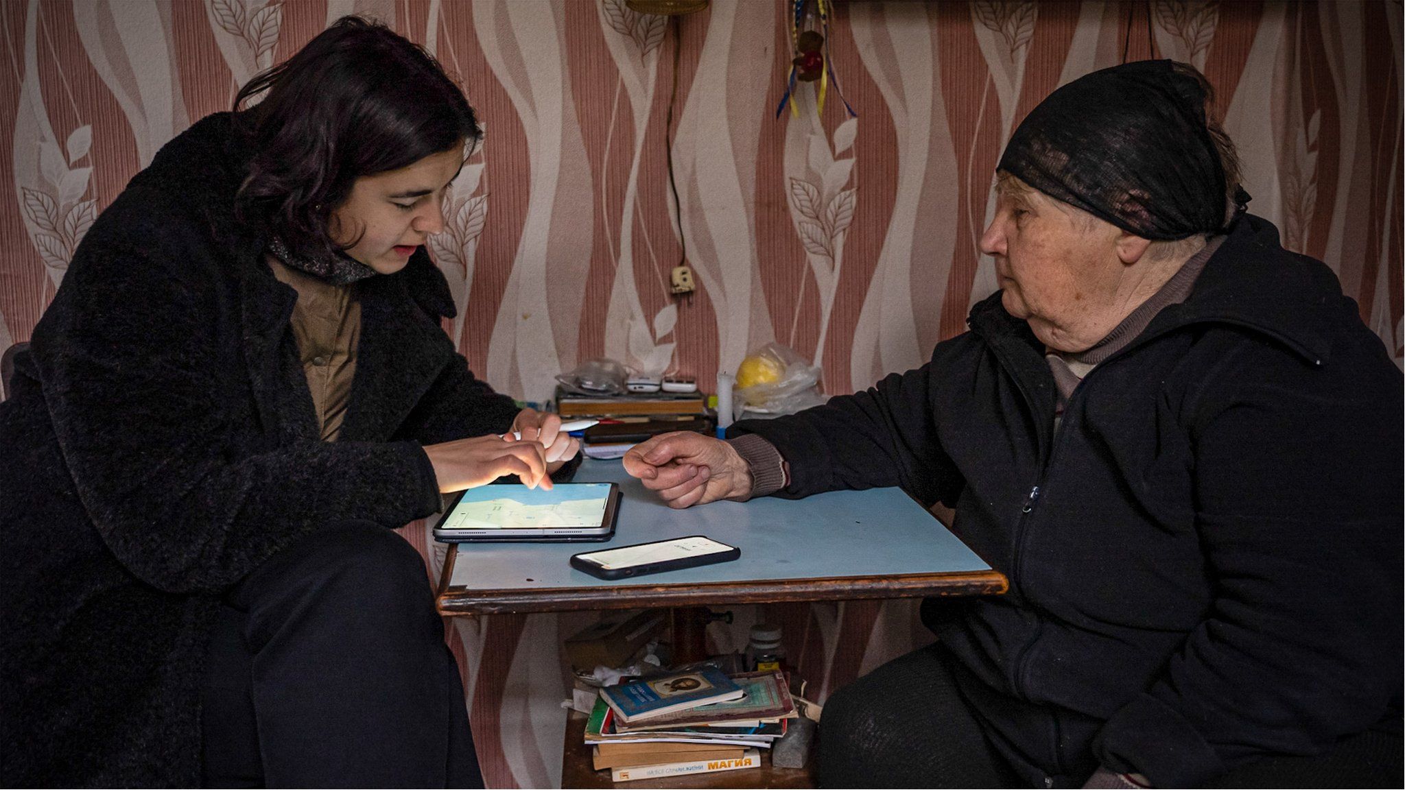 Luibov Demydiv (R), a pensioner from Demydiv, points on the map to where she saw the convoy circling after a bridge was destroyed, stopping their advance