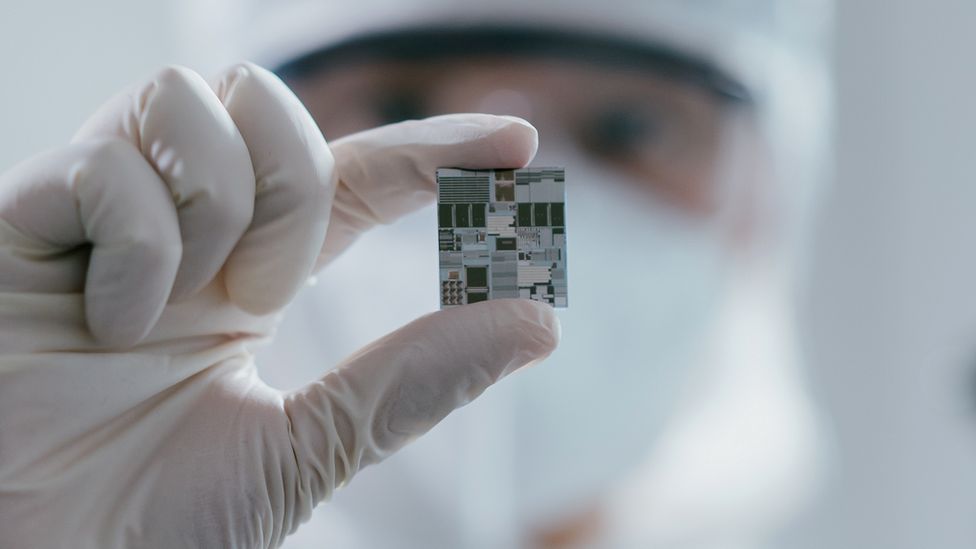 A female engineer inspects a wafer chip.