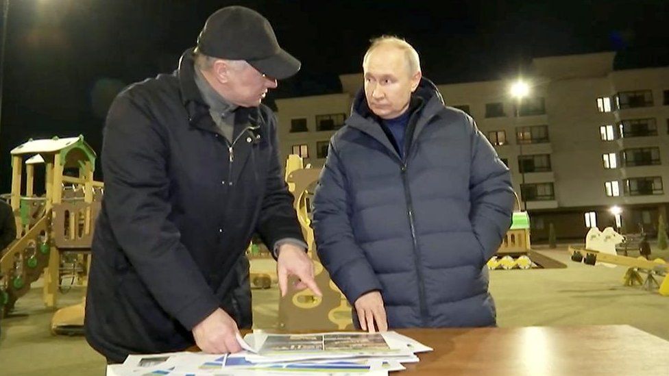 Russian President Vladimir Putin listens to Deputy Prime Minister Marat Khusnullin outside residential block in Mariupol