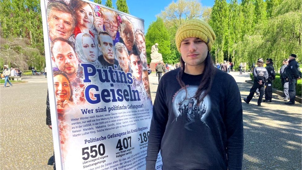 Kirill, with a poster of political prisoners in Russia, says he left the country to avoid being drafted into the Russian army