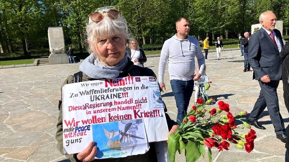 Kristina attends a demonstration with a sign criticising the West's supply of weapons to Ukraine