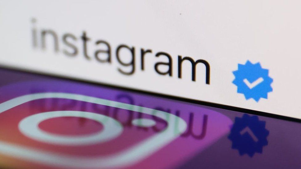 Instagram logo displayed on a smartphone with a blue verification badge
