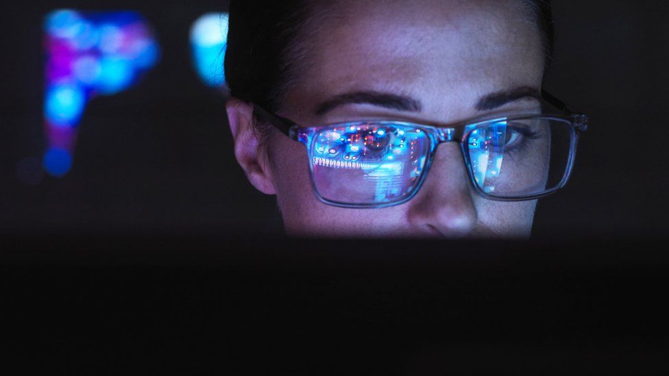 Engineer designing AI technology with computer screen reflecting on their glasses