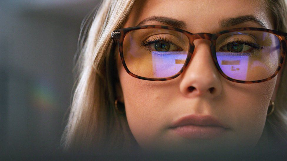 Clop. Крупным планом изображение женщины, смотрящей на компьютер, экран которого отражается в очках