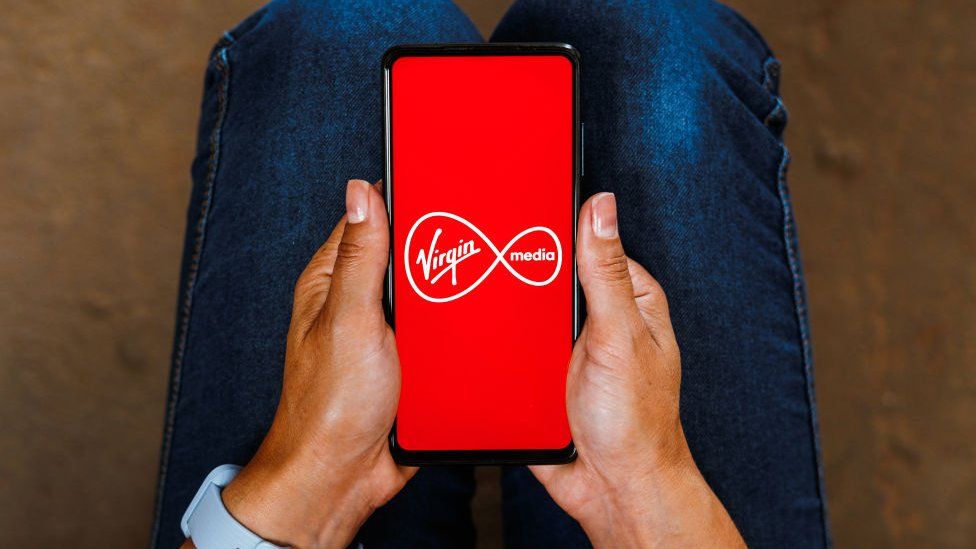 A stock image of a phone displaying the Virgin Media logo