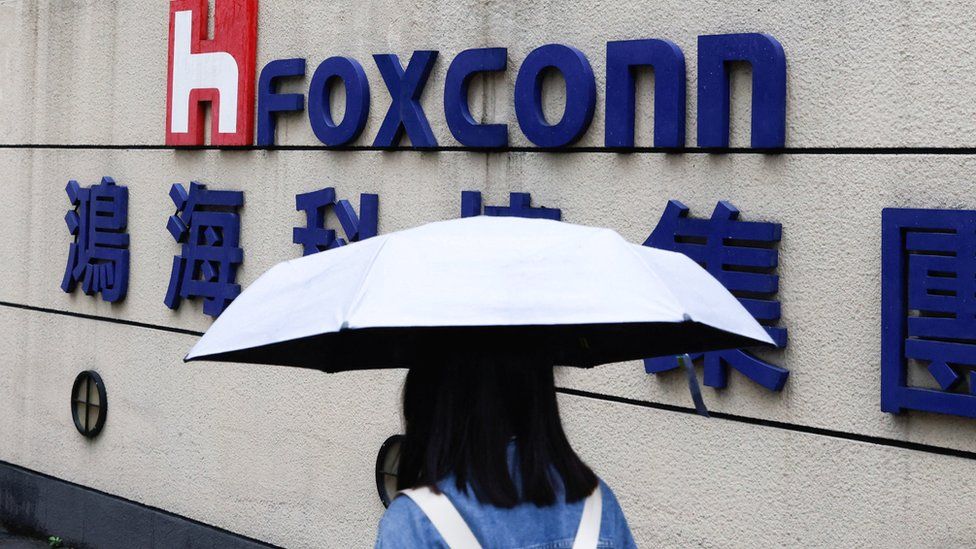 A woman carrying an umbrella walks past the Foxconn building in Taipei.