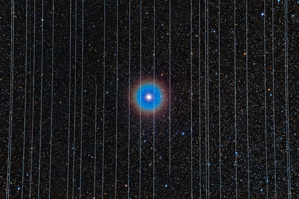 Снимок с длительной экспозицией, на котором двойная звезда Альбирео визуально загорожена пролетающими по небу спутниками Starlink.