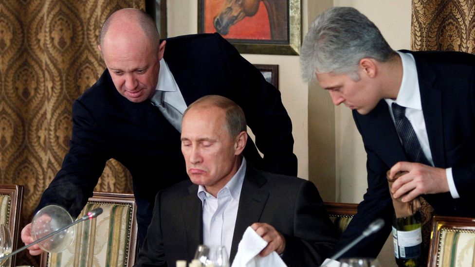 Yevgeny Prigozhin (left) pictured serving Vladimir Putin (centre) at a dinner in 2011