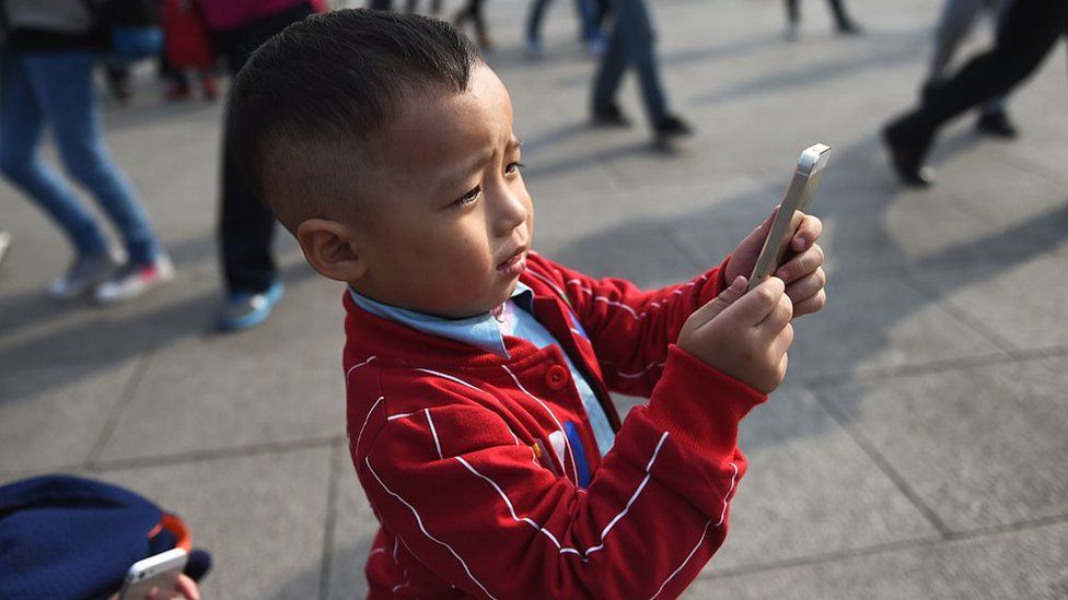 A young boy uses an iPhone to take photos in Beijing.