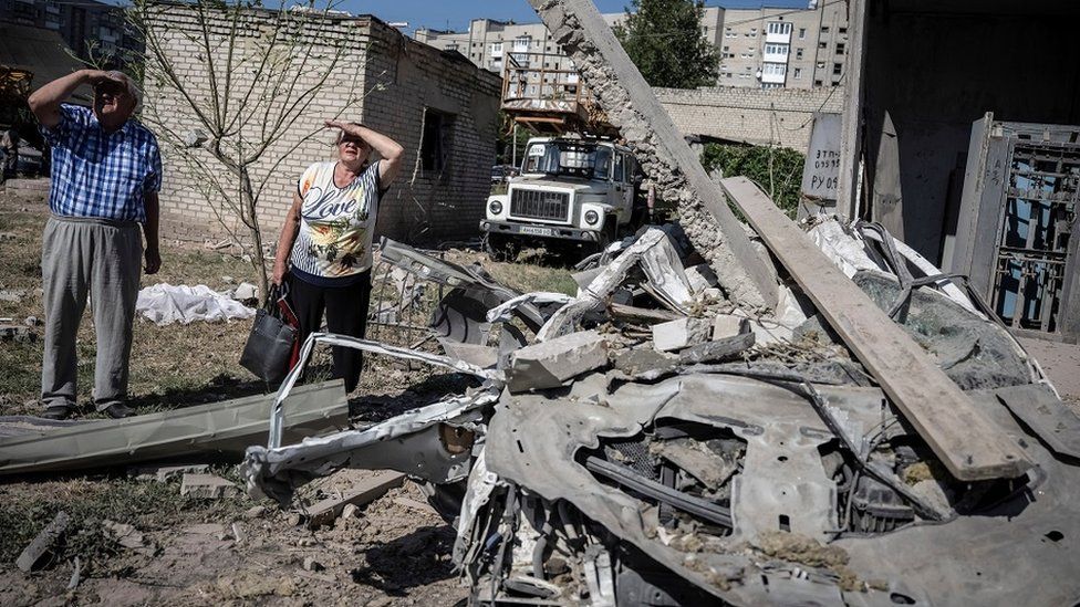 Local residents stand outside an apartment building damaged by a Russian missile strike in Pokrovsk, in the Donetsk region
