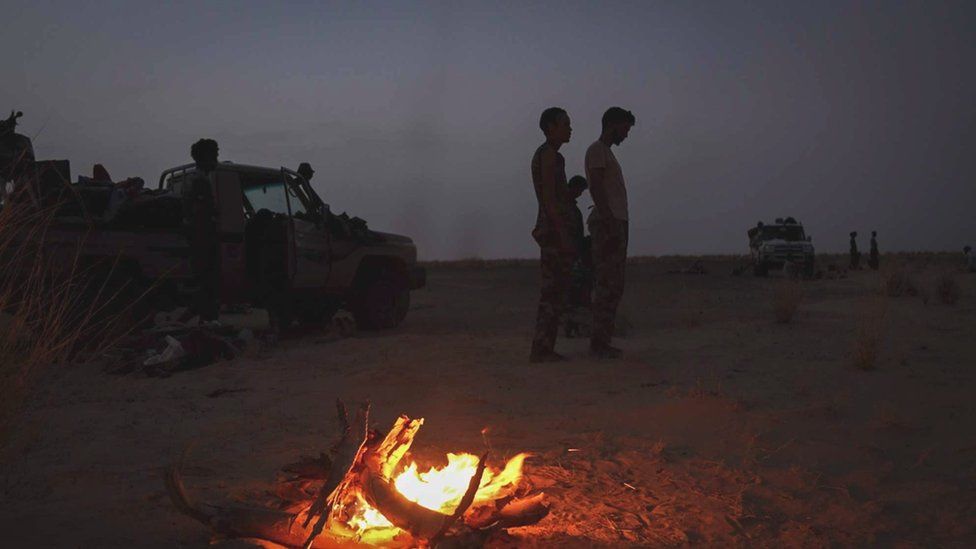 People gather near a camp fire in Mali's desert