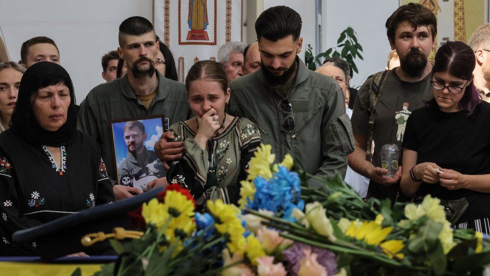 Mourners at the wake held photos of Andriy Pilshchykov, who served in the 40th tactical aviation brigade