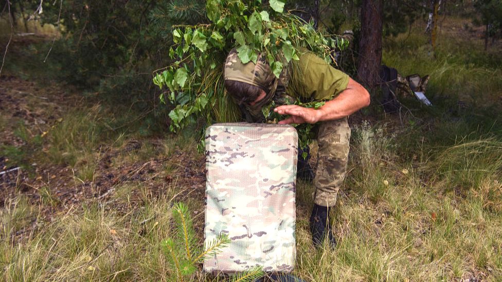 A Ukraine soldier sets up a camouflaged Starlink terminal during a military exercise