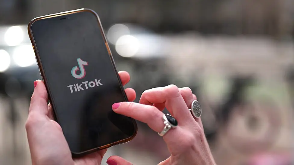 Человек использует мобильный телефон с логотипом TikTok