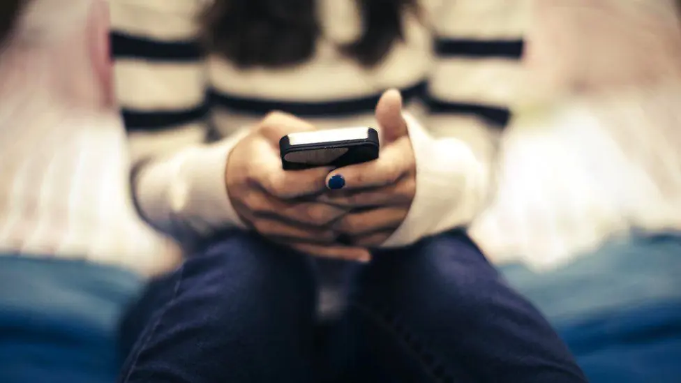 Стандартное изображение девочки-подростка, пользующейся смартфоном, видны только ее руки